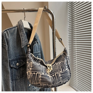 Detail of striped canvas hobo bag with wide shoulder strap and dual rope zipper pulls