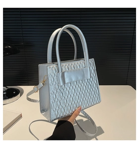Gros plan du sac cabas argenté montrant la texture matelassée 3D et les motifs gaufrés