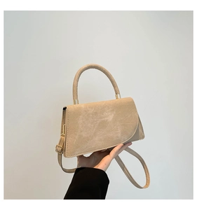 Dettaglio borsa beige con manico semicircolare e componenti in metallo dorato chiaro