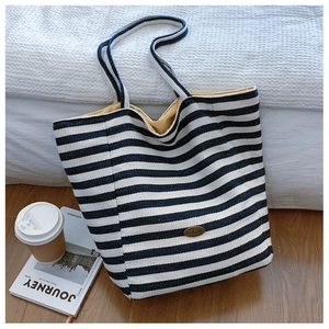 Detail of striped canvas tote bag showing yellow lining and retro metal plaque label