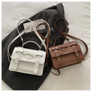 Detail of cream and brown messenger bags featuring heart embossing and bow accents