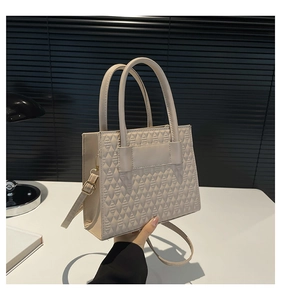 Détail du sac beige matelassé avec garnitures dorées et doubles poignées rondes