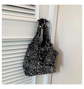 Detail of a black sequin tote bag showing sparkling texture and wide shoulder strap