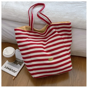 Detail of red and white striped canvas tote bag with a golden handmade metal label