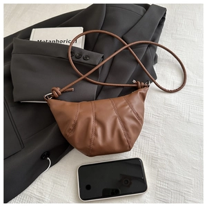Close-up of brown pleated leather crescent bag with stylish vertical stitching detail