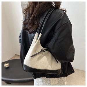 Detail of canvas tote bag with herringbone pattern and black leather trim on model