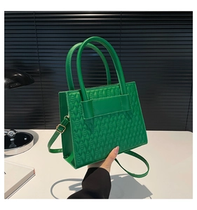 Vue détaillée du sac à main vert vif avec motif matelassé géométrique et doubles poignées