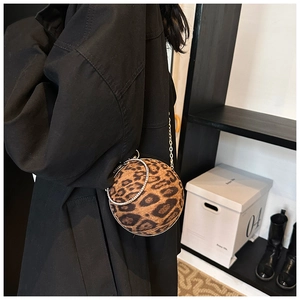 Chic leopard print sphere crossbody bag with crystal handle shown on a black trench coat