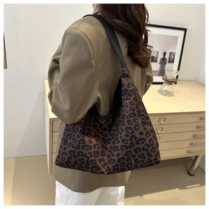 Close-up of leopard print tote bag with soft fabric and black shoulder strap on a model
