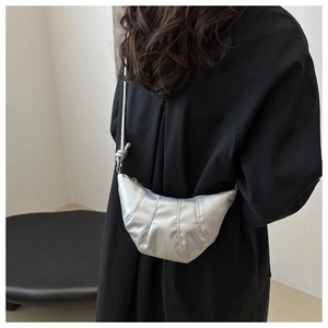 Detailed view of silver crescent bag with pleated metallic texture on female model