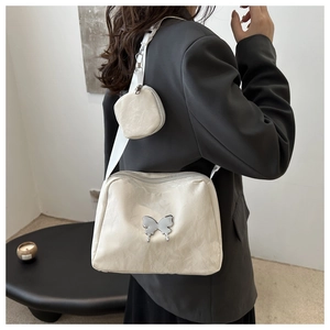 Detail of off-white crossbody pillow bag with silver butterfly and small coin pouch