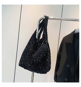 Detailed shot of black sequin tote bag with matching chain pouch on a metal display stand