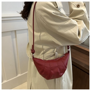 Detail of dark red crescent bag featuring pleated seams and knotted leather shoulder strap