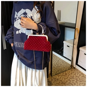 Detail of burgundy velvet crossbody bag with white polka dots and pearl top handle
