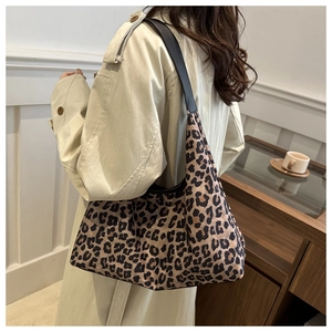 Detailed side view of leopard print shoulder bag with black leather strap on a model