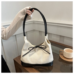 Close-up of herringbone canvas tote bag with black leather straps and bow detail