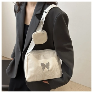 Detailed view of cream nylon crossbody bag with silver butterfly and mini coin pouch