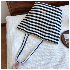 Detailed shot of striped canvas tote with yellow lining and handmade metal badge label