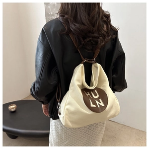 Detail view of off-white canvas hobo tote bag featuring a leather HULN logo patch