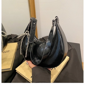 Detailed close-up of glossy crinkled leather hobo bag with silver beaded bow ornament