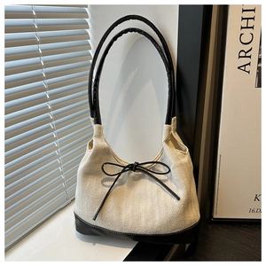 Detailed view of beige herringbone canvas fabric with black leather straps and bow