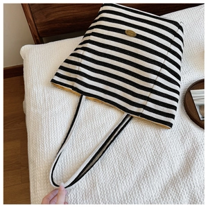 Detail of striped canvas tote bag with yellow lining on a white waffle texture surface