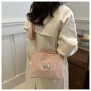 Detailed shot of pink pleated crossbody bag with silver butterfly charm and coin purse
