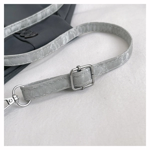 Détail de la bandoulière réglable à motif marbre avec boucles argentées sur un sac gris