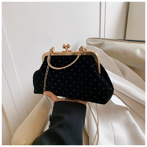 Detail of vintage black velvet shell bag featuring white polka dots and gold chain strap