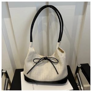 Close-up of white herringbone fabric and black leather bow on a shoulder bag