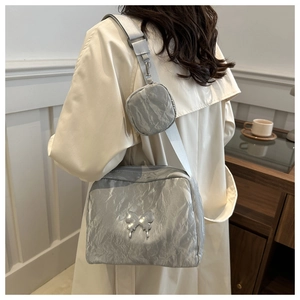 Detail of silver metallic crossbody bag with textured pleats and butterfly buckle detail