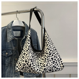 Detail of large black and white leopard print tote bag hanging next to denim jacket