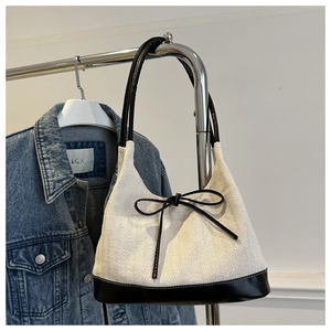 Detail of herringbone canvas tote featuring a black leather bow and slim shoulder strap