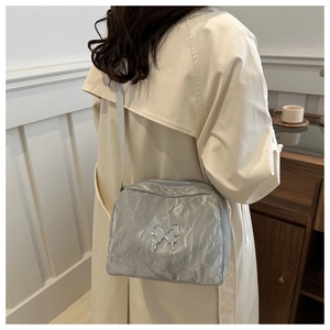 Detail of grey pleated shoulder bag with metallic silver butterfly charm in Y2K style