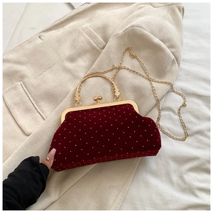 Detailed close-up of dark red velvet shell bag with white beads and gold metal handle