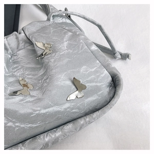Détail macro du sac argenté texturé avec des ornements en forme de papillons métalliques