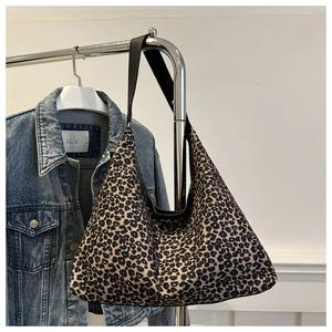 Detail of large leopard print tote bag with black leather shoulder strap and canvas texture