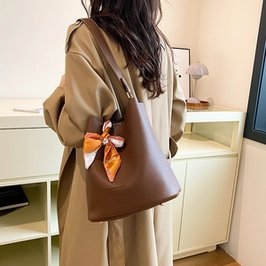 Brown lychee leather bucket bag with printed silk scarf shown on model in warm interior