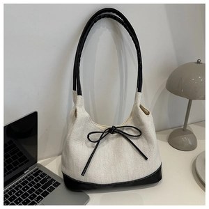 Close-up of contrast stitching canvas tote bag with black leather trim and bow detail