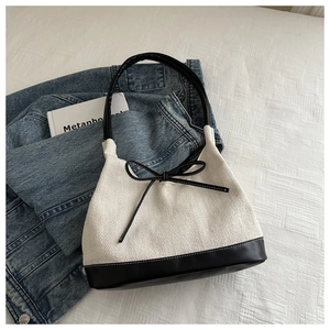 Detail of the herringbone fabric texture and leather bow accent on a stylish tote bag