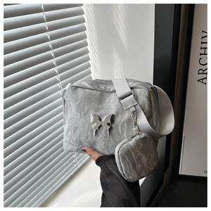 Detail of silver textured crossbody bag featuring a metal butterfly and mini coin pouch