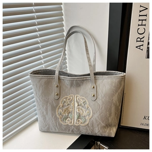 Détail du sac cabas gris avec broderie chinoise et texture à effet plissé chic