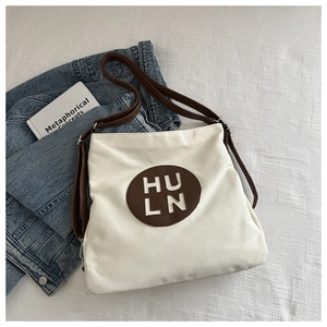 Flat lay of canvas tote bag with leather strap, HULN emblem and aesthetic props