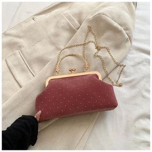 Close-up of burgundy polka dot velvet shell bag with gold clasp and chain strap