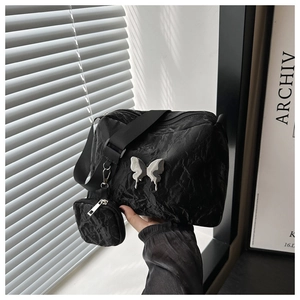 Close-up of black pleated shoulder bag with silver butterfly and small coin purse