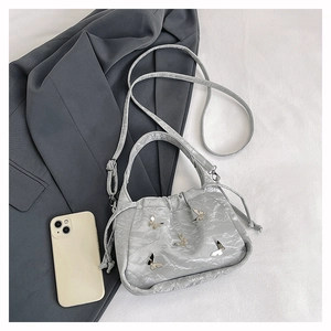Détail du sac à main argenté plissé avec papillon en métal 3D et fermeture cordon