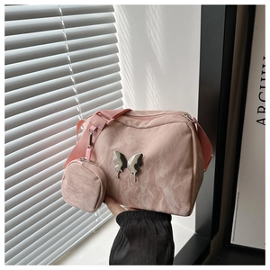 Detailed view of pink nylon dumpling bag with silver butterfly charm and mini pouch