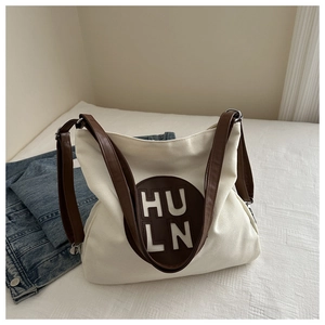 Detail of canvas tote bag with brown leather patch and adjustable metal buckles