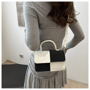 Moderna borsa a tracolla a scacchi bianchi e neri su modella con elegante finitura lucida