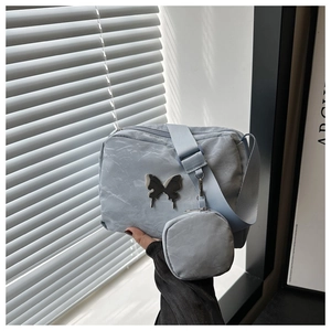 Detail of light blue nylon shoulder bag with silver butterfly logo and mini pouch